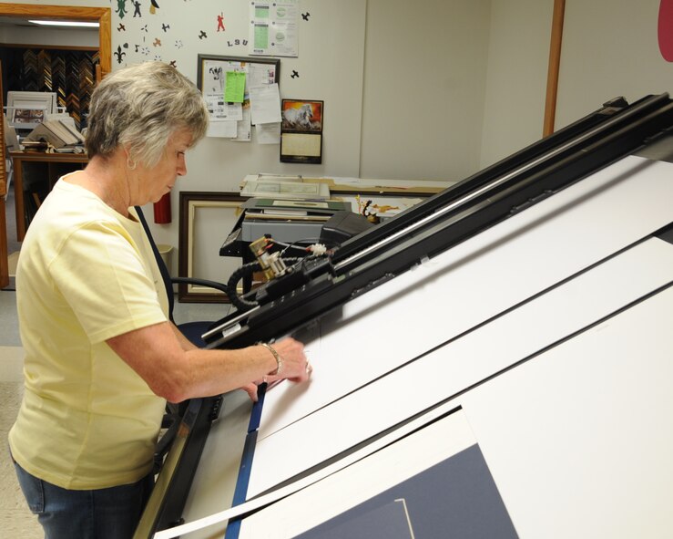 Bobbie Romano, 2nd Force Support Squadron frame shop employee, cuts a mat at the frame shop on Barksdale Air Force Base, La., July 23, 2013. A mat is used to border a picture before it is framed. (U.S. Air Force photo/Senior Airman Sean Martin)


