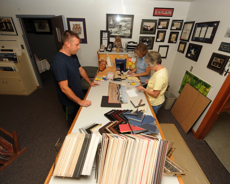 Brenda Porter and Bobbie Romano, 2nd Force Support Squadron frame shop employees, show Master Sgt. Kevin Rowe, 96th Aircraft Maintenance Unit production superintendent, different frame options at the frame shop on Barksdale Air Force Base, La., July 23, 2013. The frame shop supplies base personnel with various sized frames that are custom assembled according to the customer's specifications. (U.S. Air Force photo/Senior Airman Sean Martin)

