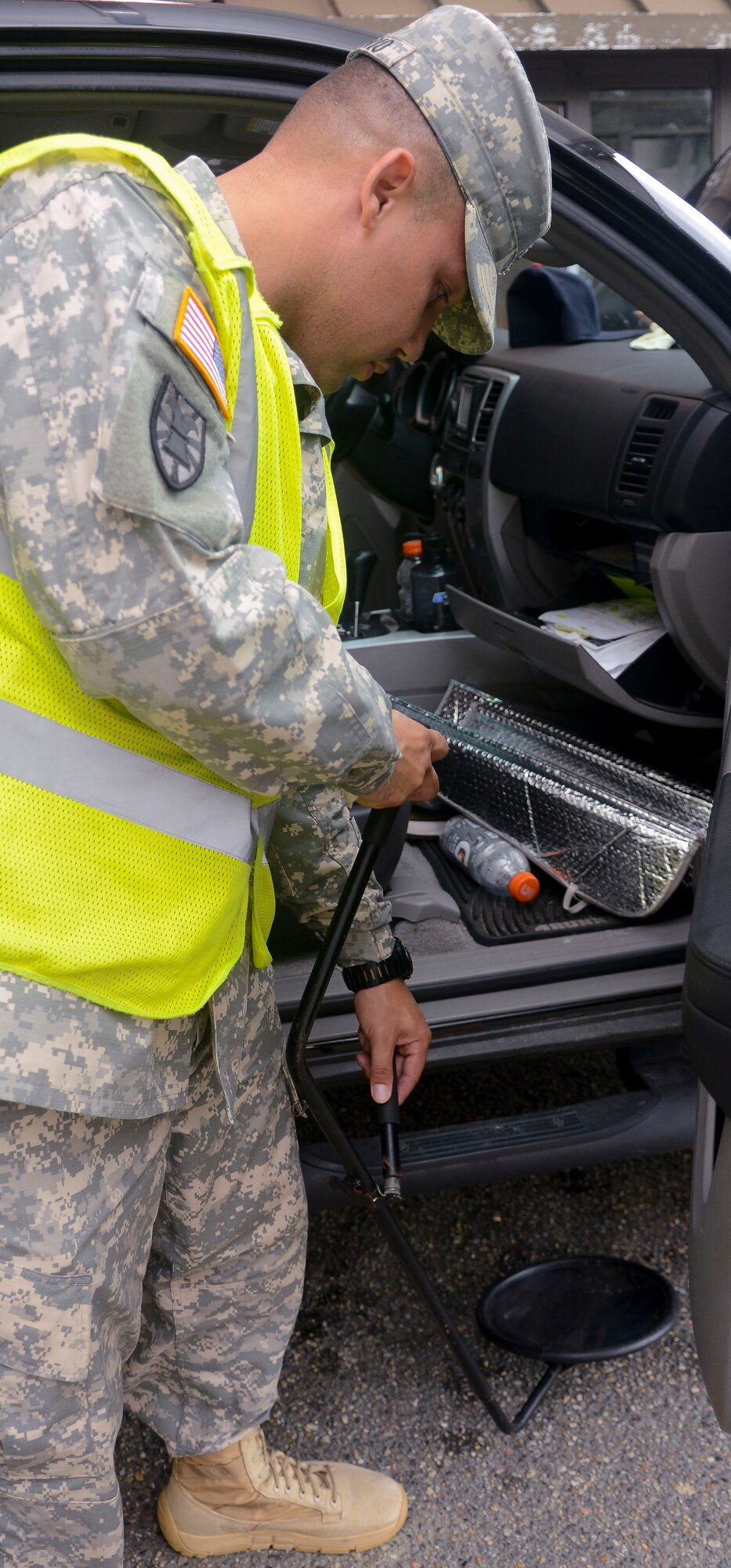 U.S. Army Sgt. Rafael Rosario, 7th Sustainment Brigade gate guard augmentee, checks the undercarriage of a vehicle for any abnormalities, at Fort Eustis, Va., July 11, 2013. Soldiers check the entire interior of every vehicle to ensure the safety of the installation. (U.S. Air Force photo by Airman 1st Class Austin Harvill/Released)
