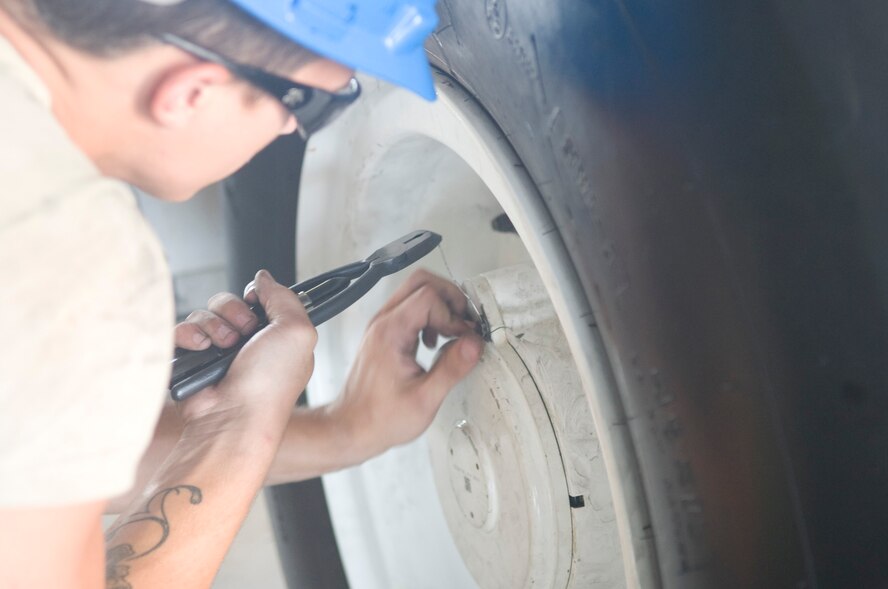 An Airman threads wiring through bolts on the wheel covering of a C-5M Super Galaxy July 19, 2013, at Dover Air Force Base, Del. All bolts are secured with wire to ensure vibrations do not loosen them. (U.S. Air Force photo/Senior Airman Jared Duhon)