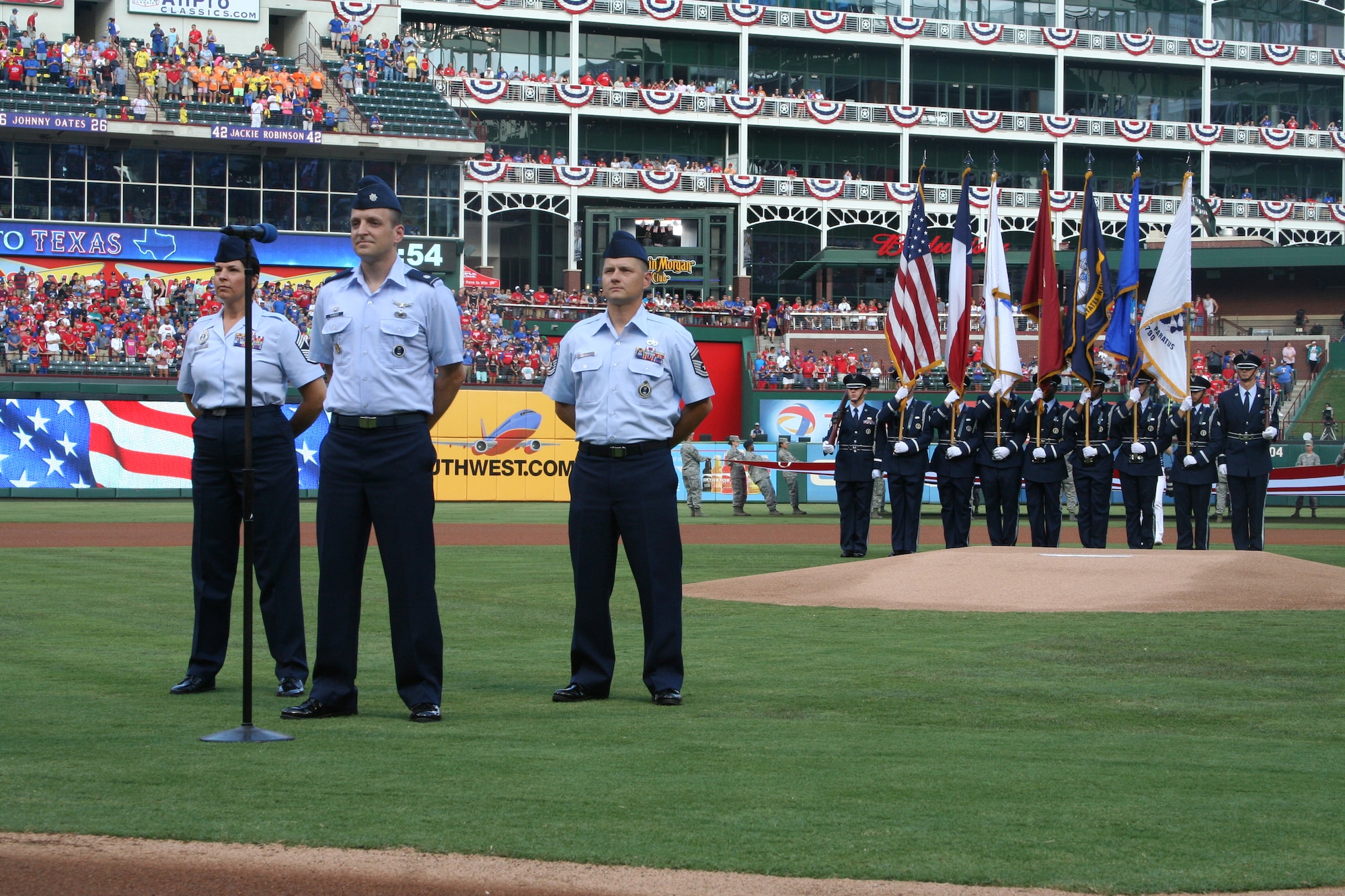 (l-r) Chief Master Sgt. Dianne Jones, 344 RCS squadron superintendent, Lt. Col. Benjamin Forest, 344 RCS commander, and Senior Master Sgt. Todd Maloney, 344 RCS production superintendent, administered the oath to 168 Delayed Entry Program members who were lined up on the first and third base lines in a pregame ceremony in front of an audience of 47,000 baseball fans at a Texas Rangers game in Arlington, Texas July 4. (U.S. Air Force photo/Staff Sgt. Cameron Wiley)