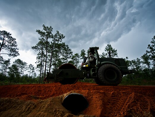 A Soldier, with the 877th Engineering Battalion from Alabama National Guard, rolls across the newly laid clay over a culvert on Range Road 211as a storm rolls in July 22 at Eglin Air Force Base, Fla.  The Army unit deployed to Eglin for eight days to work on four range projects.  Soldiers used heavy equipment to haul in and lay down clay on the RR 211 bypass road.  The road had only been sand prior to the Army taking on the job.  The work on all four projects saved Eglin approximately $176,000.  (U.S. Air Force photo/Samuel King Jr.)