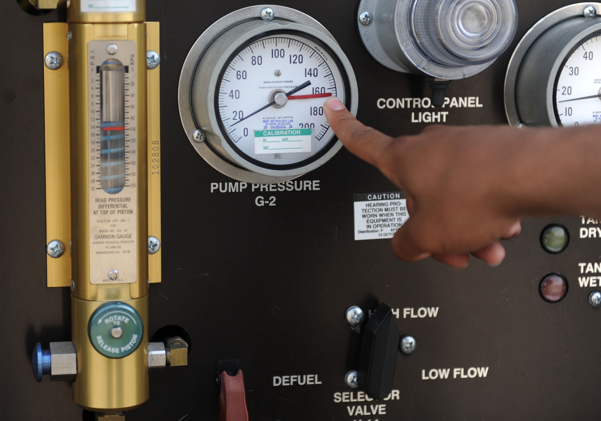 Senior Airman Jonathan Gipson, 100th Logistics Readiness Squadron Fuels Distribution operator from Lansing, Mich. points out the pump pressure gauge on an R-11 refueling truck July 22, 2013, on RAF Mildenhall, England. Safety limits are marked in red on the gauges to prevent damage to the trucks. While using the pumps of an R-11 refueling truck, Airmen must maintain very specific speeds to keep the fuel pressure under control and safe. (U.S. Air Force photo by Airman 1st Class Preston Webb/Released)