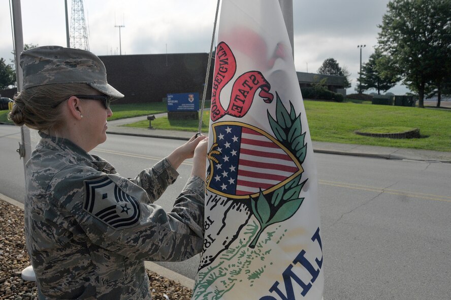 MCGHEE TYSON AIR NATIONAL GUARD BASE, Tenn. – Senior Master Sgt. Marcy Broadway, first sergeant, attaches the state flag of Illinois to a pole here on the morning of July 18, 2013. Every six months, Airmen from the I.G. Brown Training and Education Center meet on the parade ground to take down and replace the flags of the nation’s states and territories. (U.S. Air National Guard photo by Master Sgt. Mike R. Smith/Released)