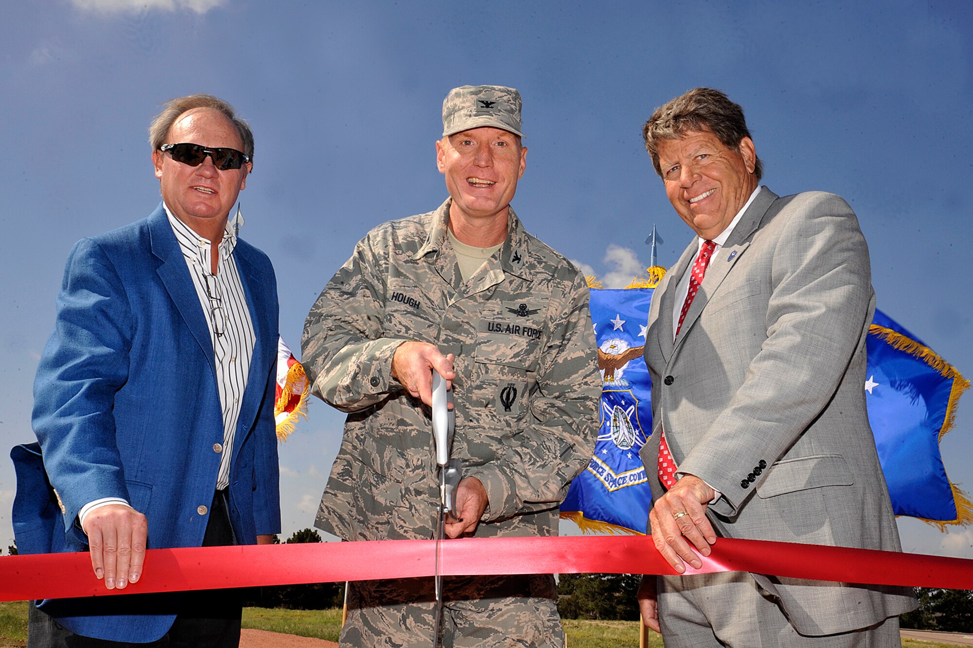 PETERSON AIR FORCE BASE, Colo. -- (Left to right) Scott Bryan, Bryan Construction, Col. Michael Hough, 21st Space Wing vice commander, and Don Addy, Colorado Thirty Group, cut a ceremonial ribbon opening a new running track here July 16. The gravel running track, which was funded by a gift to the Air Force from the private organizations, is located east of building 3 and open to all personnel with base access. (U.S. Air Force photo/Dennis Howk)
