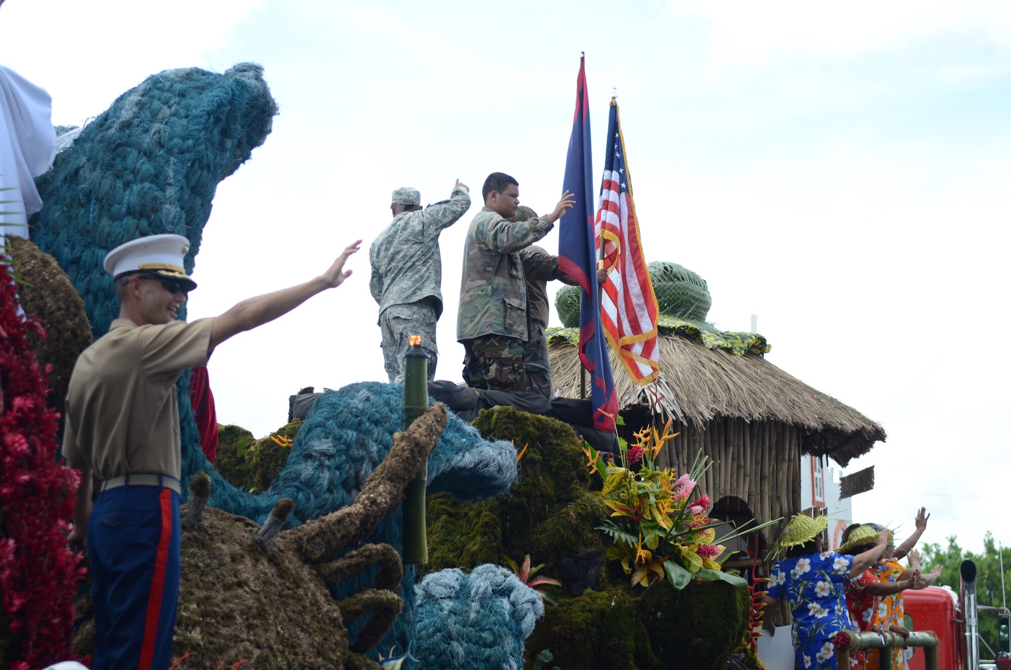 Service members join residents of Santa Rita, Guam, on the village’s float to wave as they pass the crowd during the 69th Liberation Day parade in Hagåtña, Guam, July 21, 2013. The parade commemorated the United States freeing the island from imperial Japan’s control during the Second Battle of Guam, which began July 21, 1944, and lasted for 21 days. (U.S. Air Force photo by Staff Sgt. Brok McCarthy/Released)