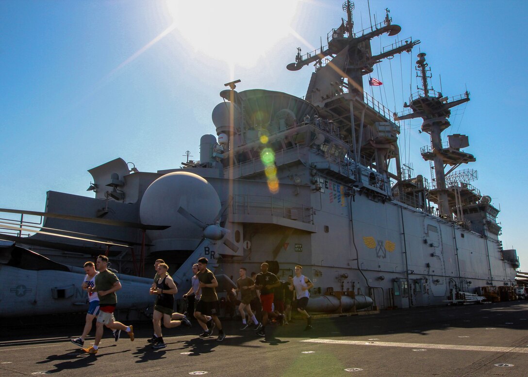 U.S. Marines assigned to Battalion Landing Team 3/2, 26th Marine Expeditionary Unit (MEU), run past the super structure of the USS Kearsarge (LHD 3), at sea, July 23, 2013. The 26th MEU is a Marine Air-Ground Task Force forward-deployed to the U.S. 5th Fleet area of responsibility aboard the Kearsarge Amphibious Ready Group serving as a sea-based, expeditionary crisis response force capable of conducting amphibious operations across the full range of military operations. (U.S. Marine Corps photo by Sgt. Christopher Q. Stone, 26th MEU Combat Camera/Released)