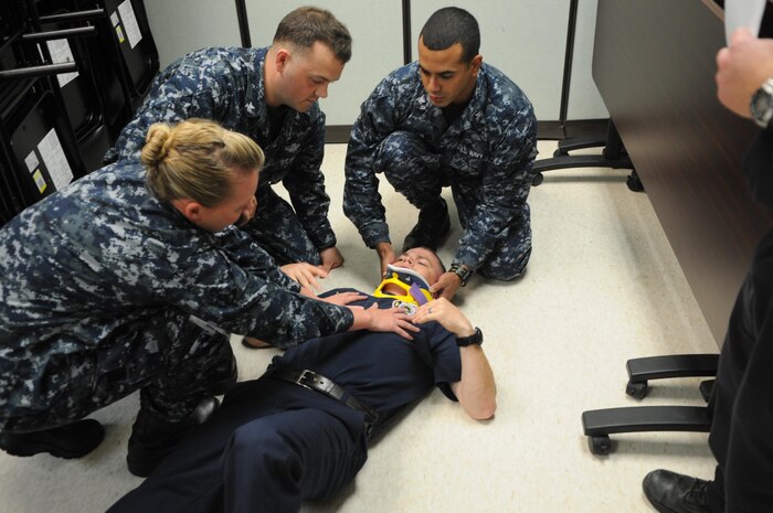 Naval Health Clinic Quantico corpsmen Lt. j.g. Stephanie Beatty, Petty Officer 3rd Class Jonathan Fowler and Petty Officer 3rd Class Abraham Milan assess Firefighter/Paramedic Joshua Waddell’s injuries in a training scenario July 18, during the International Trauma Life Support training the clinic and base firefighters held together last week. 