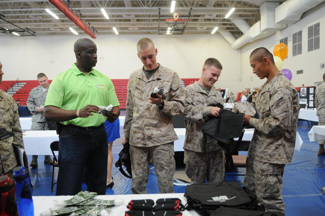 From left, Milton Young, alcohol abuse prevention specialist for the Consolidated Substance Abuse Counseling Center, looks on as Pfc. Joseph Campo, Pfc. Thomas Bonome and Pfc. Christopher Denkovic, all new to the base Motor Transport Maintenance Section, check out the satchels and other goods CSACC was distributing at the Quantico Welcome Aboard brief July 17. 