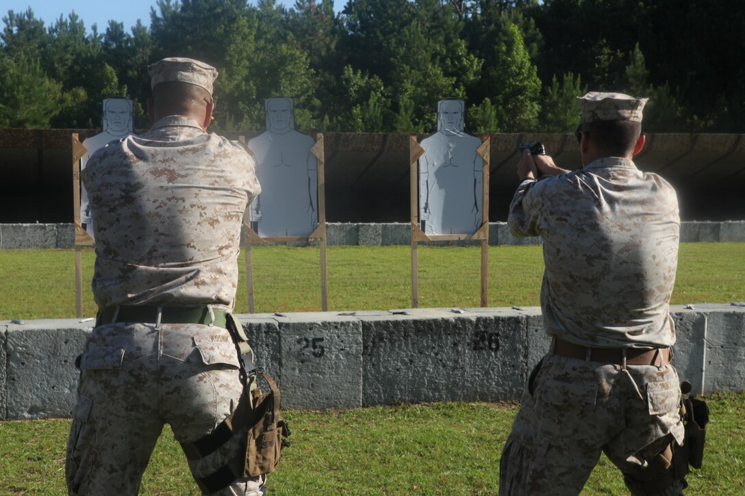 Capt. Steven L. Kosnik, Weapons Training Battalion operations officer at Stone Bay Rifle Range, a satellite installation of Marine Corps Base Camp Lejeune, left, and Capt. Patrick Port, a Weapons Training Battalion company commander at Stone Bay Rifle Range, shoot their qualification course of fire during the Combat Pistol Program. Both Marines qualified with a total of 40 rounds. 