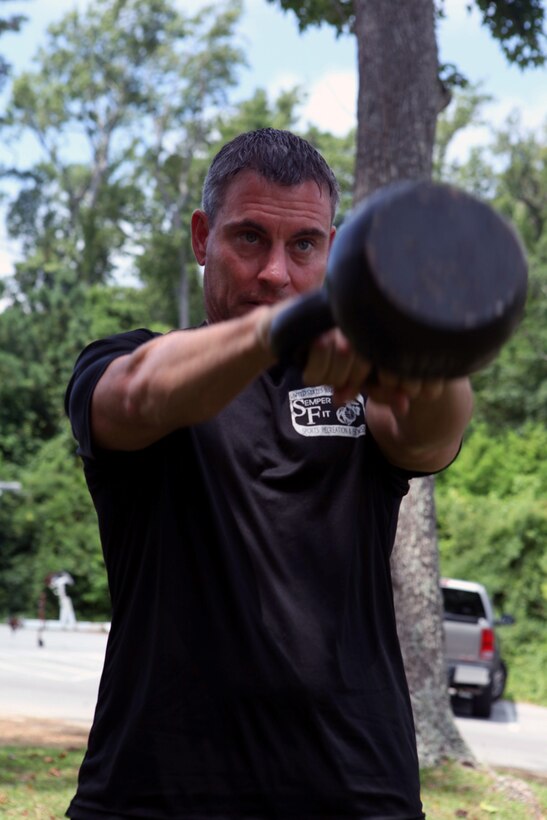 Dennis J. Yeddo, fitness facilities manager, fitness branch, Semper Fit division, Marine Corps Community Services, performs a kettle bell lift during a Paddle Fit Boot Camp workout aboard Marine Corps Base Camp Lejeune, July 23. Classes cost $7, and participants are encouraged to bring a towel, drinking water and civilian clothes to change into since most of the workout is on the water.