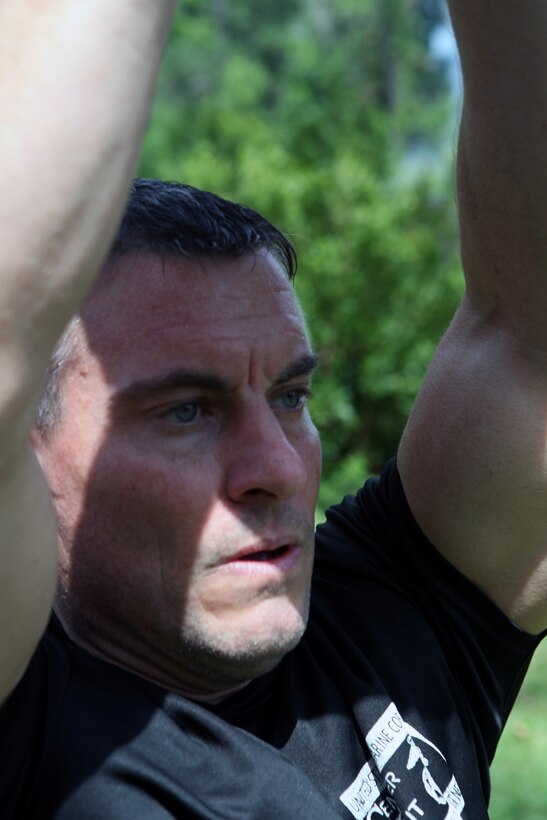 Dennis J. Yeddo, fitness facilities manager, fitness branch, Semper Fit division, Marine Corps Community Services lifts a sand bag above his head during a Paddle Fit Boot Camp workout aboard Marine Corps Base Camp Lejeune, July 23. More than 50 MCB Camp Lejeune residents and service members completed the workouts since the paddleboard exercising started in May.