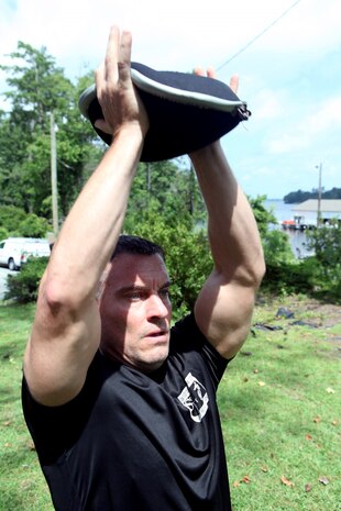 Dennis J. Yeddo, fitness facilities manager, fitness branch, Semper Fit division, Marine Corps Community Services lifts a sand bag above his head during a Paddle Fit Boot Camp workout aboard Marine Corps Base Camp Lejeune, July 23. Currently, there are 14 certified Paddle Fit instructors in Semper Fit.