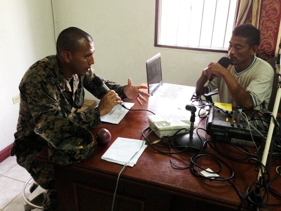U.S. Marine Cpl. Guillermo Muguerza, a civil affairs noncommissioned officer with the 4th Civil Affairs Group, discusses projects with a local radio station host, April 4. Civil Affairs Teams and Engineers from both the U.S. and Belize are constructing various structures at schools throughout Belize as part of exercise New Horizons.  (U.S. Air Force photo by Capt. Holly Hess/Released)