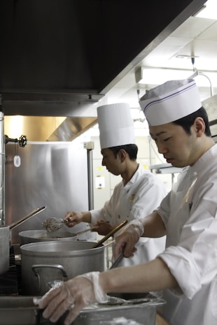 Mori Nobu, back, Club Iwakuni sous chef, assists a chef prepare food for a reception at Club Iwakuni at Marine Corps Air Station Iwakuni, Japan, July 12, 2013. With most of his time being spent on preparing events and scheduling work times  for  employees, Nobu gets to assist in cooking for large events.