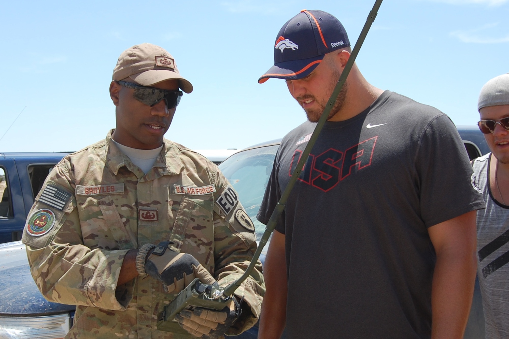 Staff Sgt. Christopher Broyles, 140th Explosive Ordnance Disposal Flight, teaches 1st Lieutenant Ben Garland, member of the 140th Wing and a player for the Denver Broncos, how to operate the remote firing device for an explosive during the EOD Demo Day July 12, 2013 at Airburst Range, Fort Carson, Colo. (U.S. Air National Guard photo by Capt. Kinder Blacke)