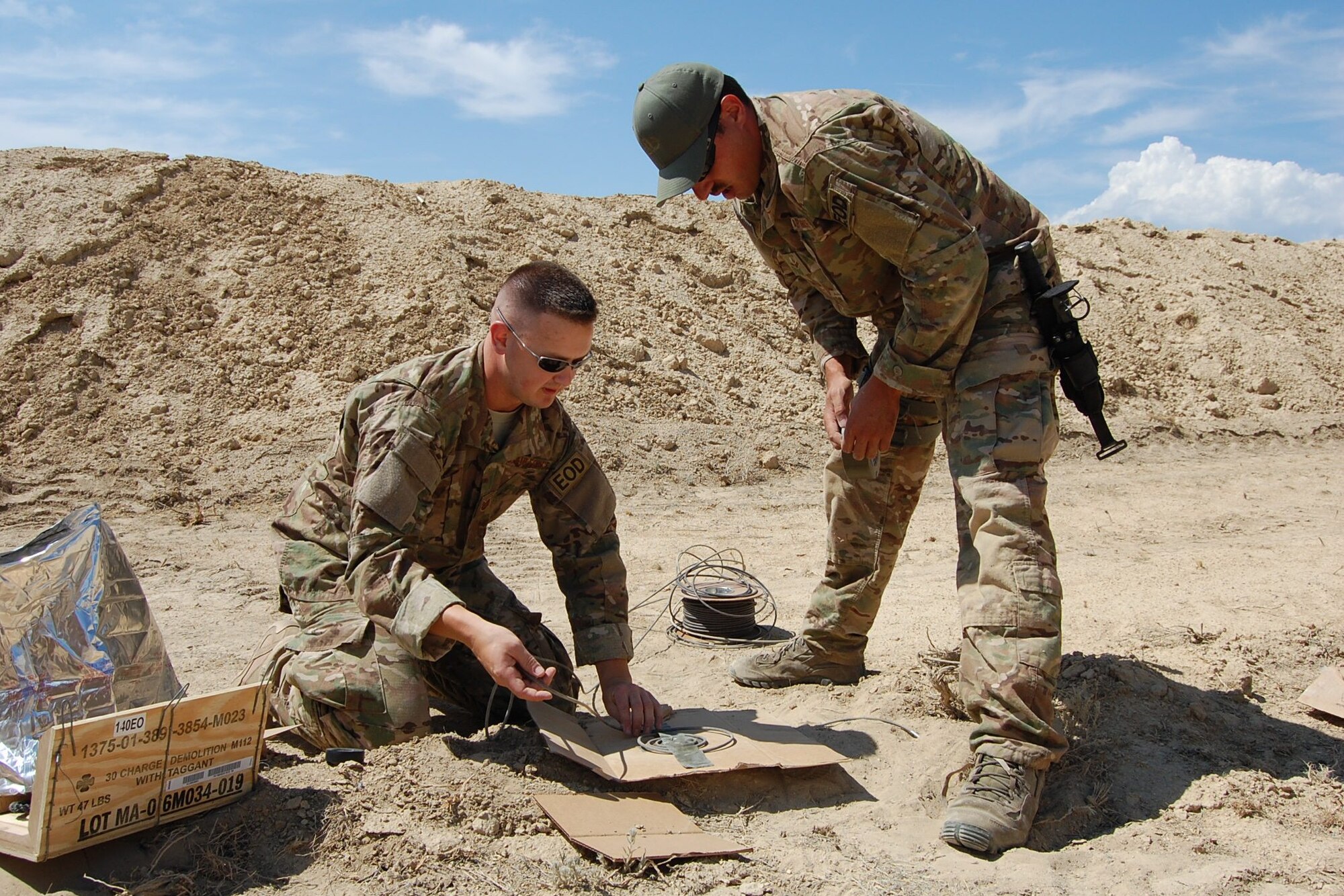 Colorado Air National Guard Tech. Sgt. Andrew LeBeau and Airman 1st Class Darrell Linkus, 140th Explosive Ordnance Disposal Flight, wrap detonation cord on cardboard for a diesel display charge during the EOD Demo Day July 12, 2013 at Airburst Range, Fort Carson, Colo. (U.S. Air National Guard photo by Capt. Kinder Blacke)