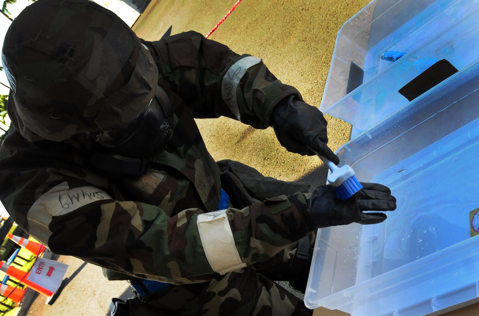 Technical Sgt. Manuel Gariby uses a brush to decontaminate his gloves before entering the compound on the last day of an Operational Readiness Exercise at Joint Base Pearl Harbor-Hickam, Hawaii, July 19, 2013.  The week-long exercise demonstrated the effective use of Total Force Integration with active duty and Hawaii Air National Guard Airmen working side-by-side to accomplish the mission. (U.S. Air Force photo/Tech. Sgt.  Michelle Thomas)  