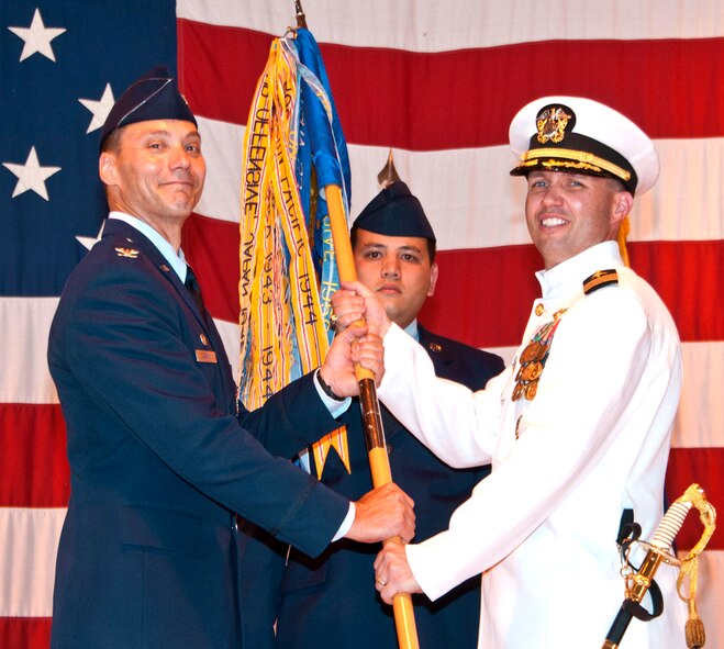 Navy Cmdr. Christopher Narducci, right, accepts the 33rd Flying Training Squadron guidon from Col. James Abatti, 71st Operations Group commander, during the 33rd FTS change of command ceremony June 25 in Hangar 170 at Vance Air Force Base, Okla. In the background is Senior Airman Johnathan Leddy, also with the 33rd FTS. (U.S. Air Force photo/ Terry Wasson)