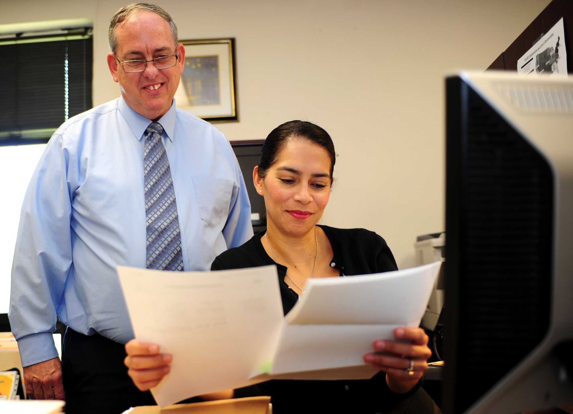 Gary Zuch, left, Medical Cost Reimbursement Program senior claims paralegal team leader, and Patricia Ramirez, MCRP paralegal specialist, discuss medical reimbursement cases in their office at Langley Air Force Base, Va., July 24, 2013. The MCRP team is responsible for managing all cases that occur in Virginia, West Virginia, North Carolina, South Carolina and Tennessee. (U.S. Air Force photo by Airman Areca T. Wilson/Released)