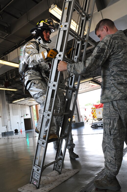 U.S. Air Force Staff Sgt. Troy Falkena, 633rd Civil Engineer Squadron firefighter, holds a ladder upright as Chief Master Sgt. Richard Parsons, command chief of Air Combat Command, completes the firefighters’ challenge at Langley Air Force Base, Va., July 17, 2013. The event included simulated chopping of a sled, dragging hoses and rescuing a life-sized mannequin while racing against the clock. (U.S. Air Force photo by Airman 1st Class Victoria H. Taylor/Released)