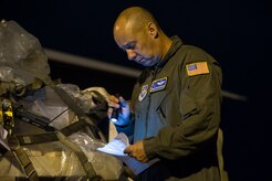 Chief Master Sgt. Jack McCracken, 40th Airlift Squadron loadmaster with the 317th Airlift Group from Dyess Air Force Base, Texas, reviews logs after loading cargo onboard a C-130 during an early morning cargo load July 23, 2013, at Joint Base Charleston - Air Base, S.C. The C-130 was loaded with rations and  supplies bound for Bogota. The C-130J-30 is a stretch version of the C-130J, a proven, highly reliable and affordable airlifter. The C-130J-30 adds 15 feet to the fuselage, increasing usable space in the cargo compartment. (U.S. Air Force photo/ Senior Airman George Goslin)