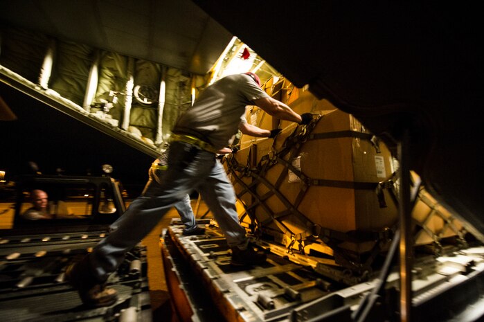 Civilians from the 437th Aerial Port Squadron push cargo onto a C-130J-30 from Dyess Air Force Base, Texas, during an early morning cargo load July 23, 2013, at Joint Base Charleston - Air Base, S.C. The C-130J-30 was loaded with rations and supplies bound for Bogota. The C-130J-30 is a stretch version of the C-130J, a proven, highly reliable and affordable airlifter. The C-130J-30 adds 15 feet to the fuselage, increasing usable space in the cargo compartment. (U.S. Air Force photo/ Senior Airman George Goslin)