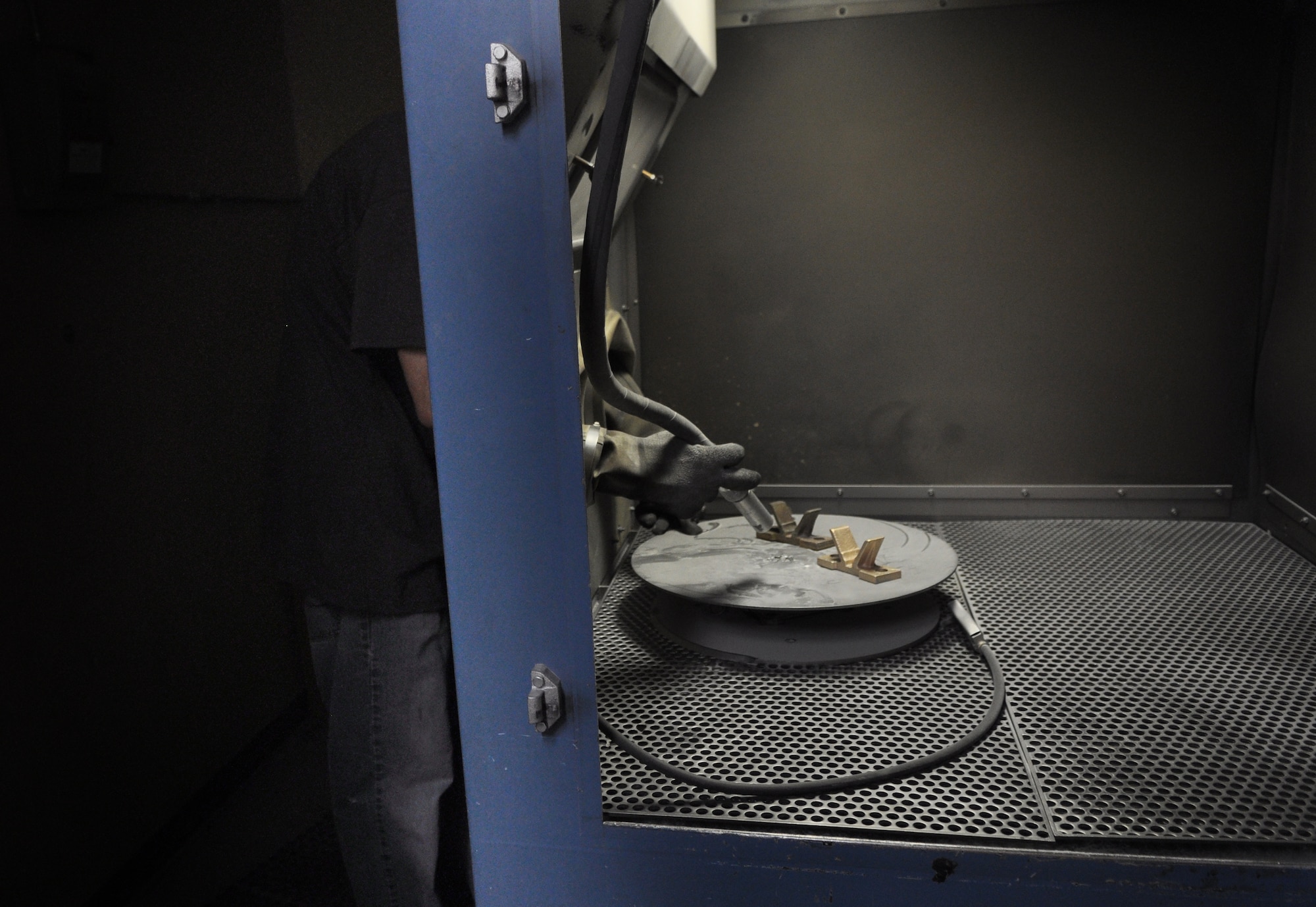 The parts for the plating tanks must be cleaned as well, here, Daniel Summers of the 548th PMXS uses glass beads as blast media to clean plating tank parts. (Air Force photo by Micah Garbarino)