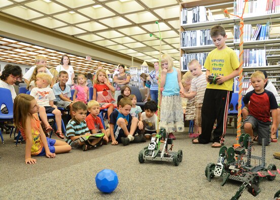 A young volunteer attempts to use the VEX Claw bot to lift a rubber ball. The base library's summer reading program invites speakers each Friday to give presentations to young children to get them interested in learning. (U.S. Air Force photo by Rebecca Amber) 
