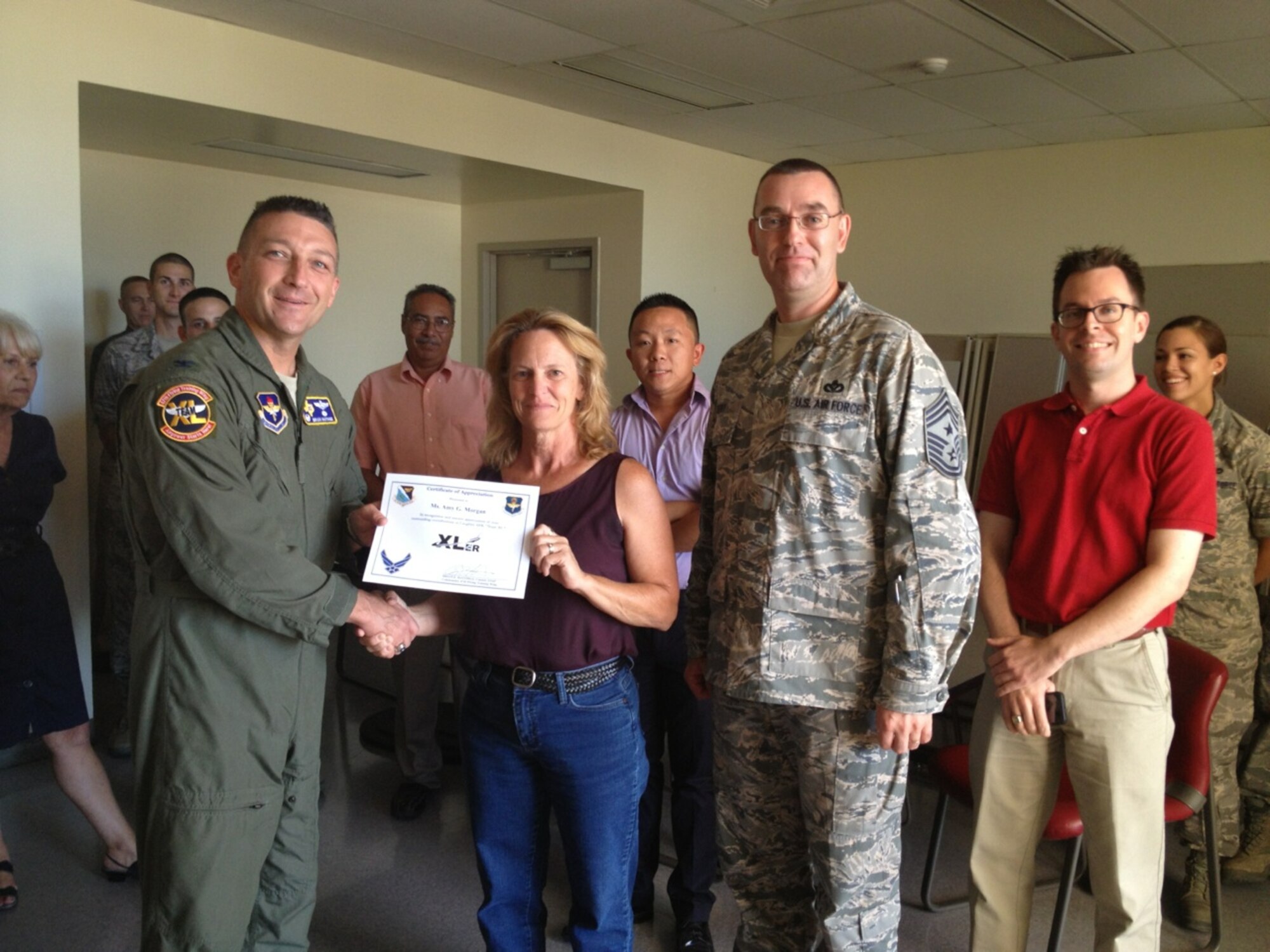 Amy Morgan, 47th Civil Engineer Squadron programmer, poses with Col. Brian Hastings, 47th Flying Training Wing commander, and Chief Master Sgt. Garry Berry, 47th FTW command chief, after being presented the XLer of the week award here July 11, 2013. The XLer is a weekly award chosen by wing leadership and given to those who consistently make outstanding contributions to Laughlin and their unit. (Courtesy photo)