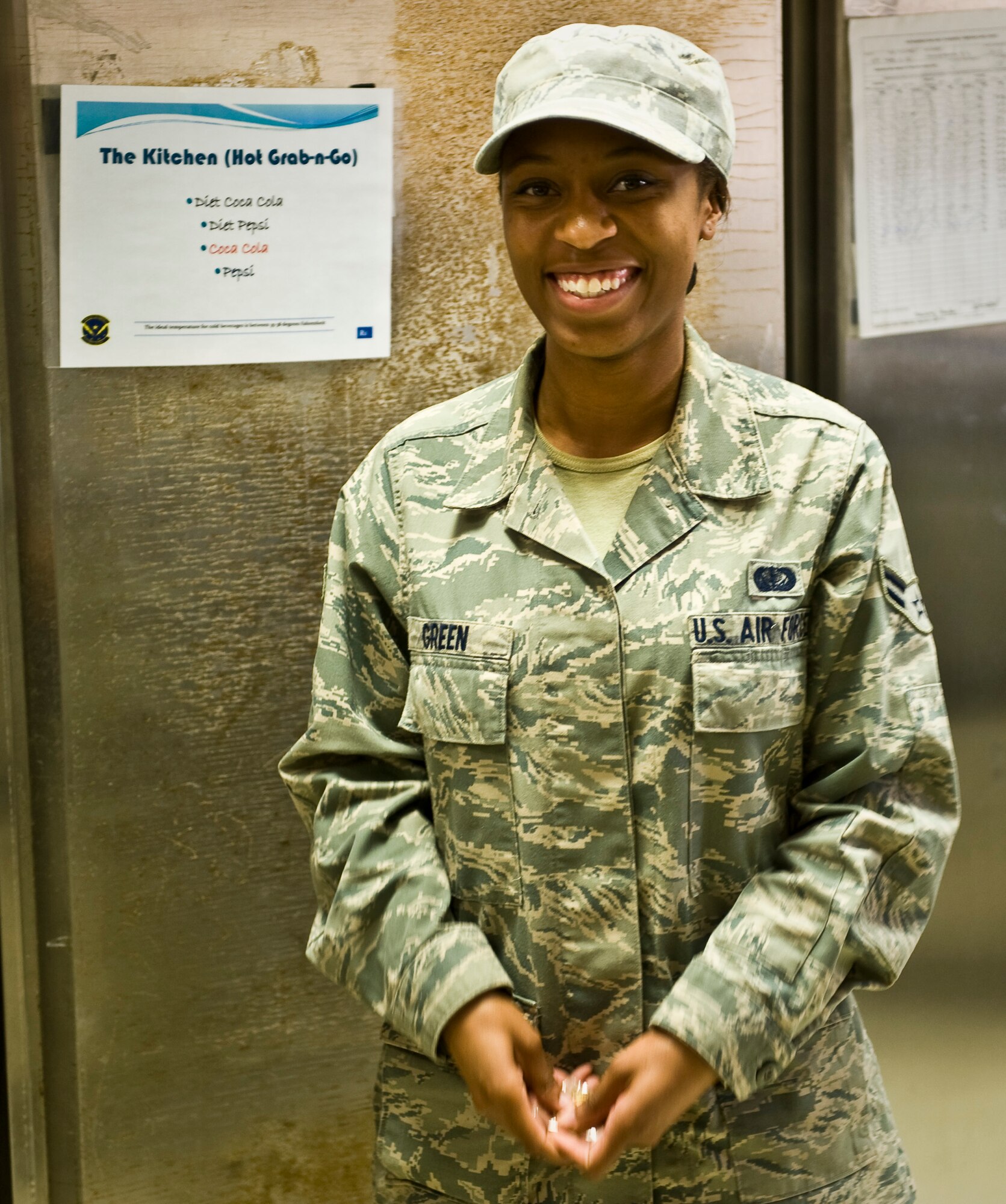 Airman 1st Class Ashli Green smiles after receiving a coin from Chief Master Sgt. Richard Lutz during a Desert Chiefs Group recognition at the 379th Air Expeditionary Wing in Southwest Asia, July 22, 2013. Green is a 379th Expeditionary Force Support Squadron quality assurance evaluator deployed from Joint Base Charleston, S.C. Lutz is the 379th Expeditionary Operations Group superintendent. (U.S. Air Force photo/Senior Airman Benjamin Stratton)