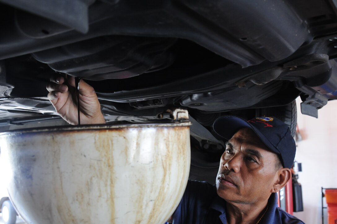 Jimmy Mendoza, Army and Air Force Exchange Service Car Care Center auto technician, drains a vehicle’s oil in pan during an oil change July 19, 2013 on Andersen Air Force Base, Guam. AAFES technicians recommend that filters and oil be changed every 3,000 miles or every three months to ensure a vehicle continues running well. (U.S. Air Force photo by Airman 1st Class Amanda Morris/Released)