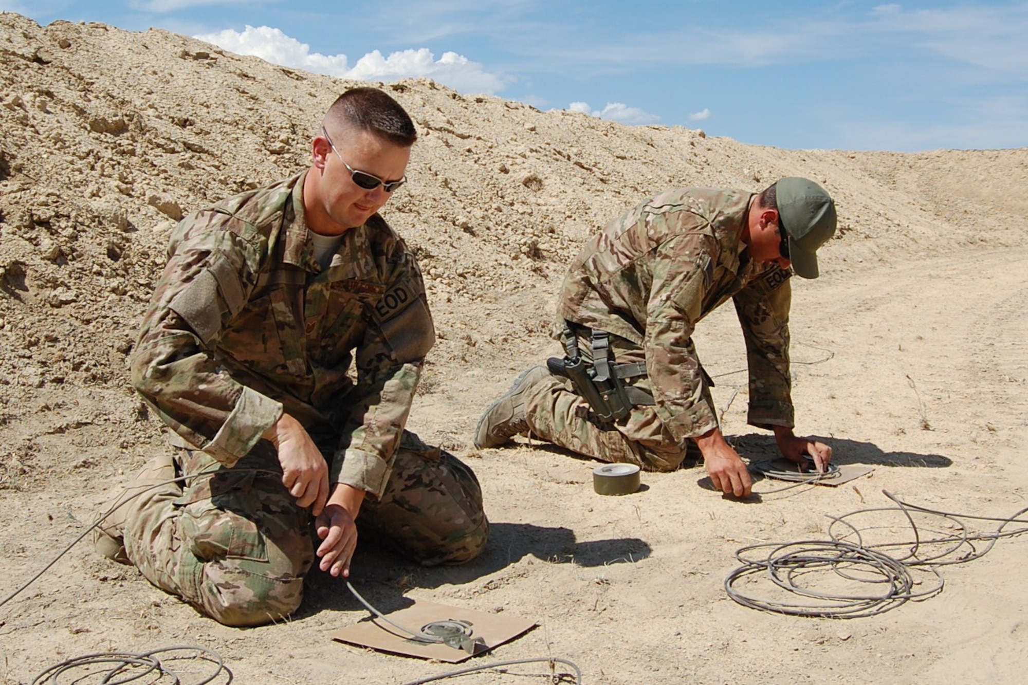 Colorado Air National Guard Tech. Sgt. Andrew LeBeau and Airman 1st Class Darrell Linkus, 140th Explosive Ordnance Disposal Flight, wrap detonation cord on cardboard for a diesel display charge during the EOD Demo Day July 12, 2013 at Airburst Range, Fort Carson, Colo. (U.S. Air National Guard photo by Capt. Kinder Blacke)