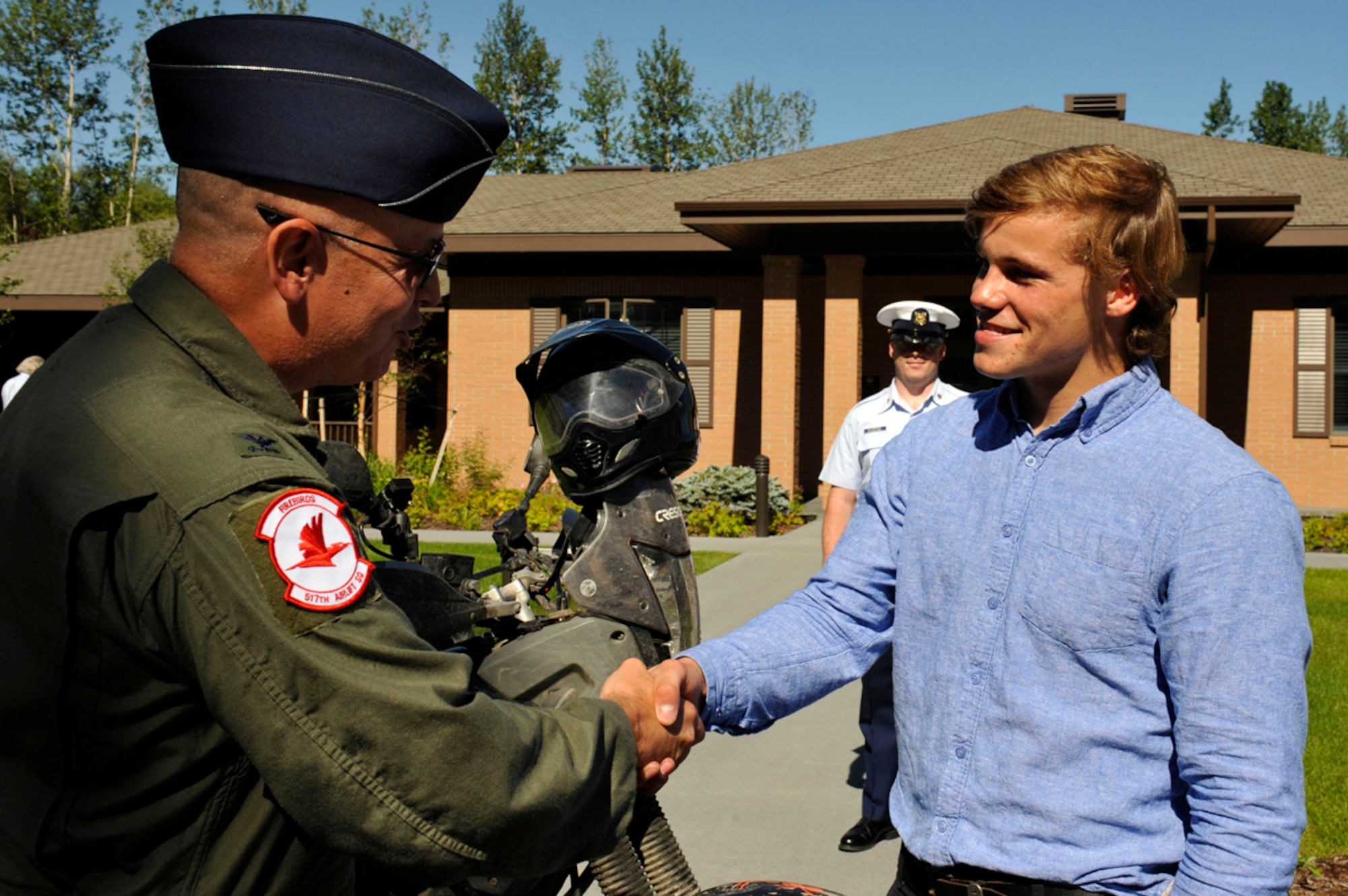 JOINT BASE ELMENDORF-RICHARDSON, Alaska-- Oliver Plunket, a native of the United Kingdom, receives a coin from Air Force Col. Thomas Harrell, 673d Medical Group commander, at the Fisher House of Alaska on Joint Base Elmendorf-Richardson July 22. Plunket received the coin as a token of appreciation for the travels he has taken to raise funds for the newly built Fisher House in the UK. He rode his motorcycle from the southernmost city in Argentina to Prudhoe Bay, Alaska, stopping at other Fisher Houses and visiting various historic sites. (U.S. Air Force photo/Airman 1st Class Tammie Ramsouer)