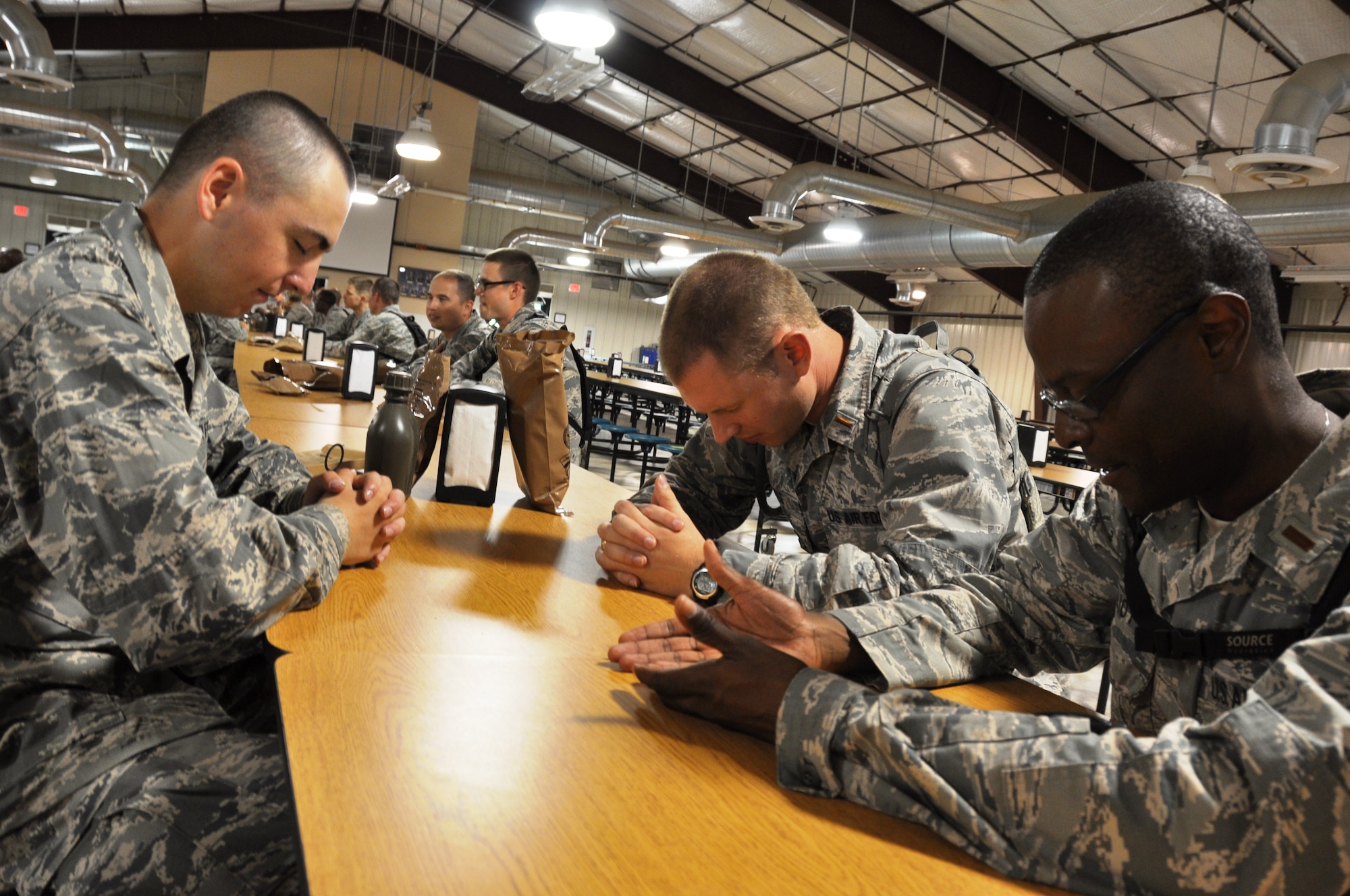 A basic trainee and Air Force chaplain candidates pray after a lunch of Meals Ready to Eat (MRE) at the Basic Expeditionary Airman Skills Training. Chaplain candidates spent time with Air Force basic trainees during their four week tour of various Air Force Bases to see if a carrer in military ministry is for them. (Air Force photo by Tech Sgt. Carlos Trevino)