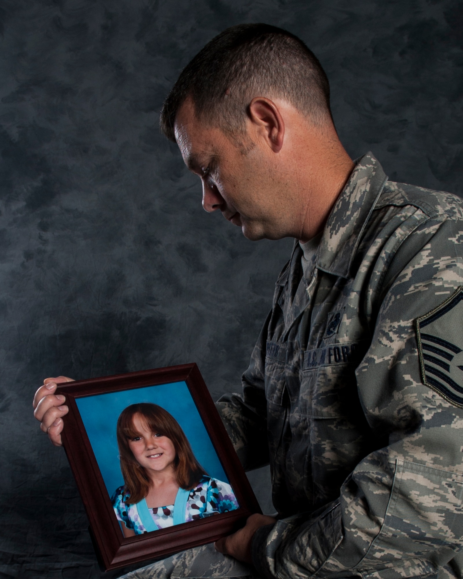 U.S. Air Force Master Sgt. Benjamin Pitts, 23d Wing Plans, Programs and Inspections superintendant of exercise and wing evaluations, looks at a picture his daughter, Elizabeth, July 22, 2013, at Moody Air Force Base, Ga. Pitts, who lost Elizabeth due to cancer in 2010 started a charity organization to assist families struggling with pediatric cancer. (U.S. Air Force photo by Airman 1st Class Sandra Marrero/Released)
