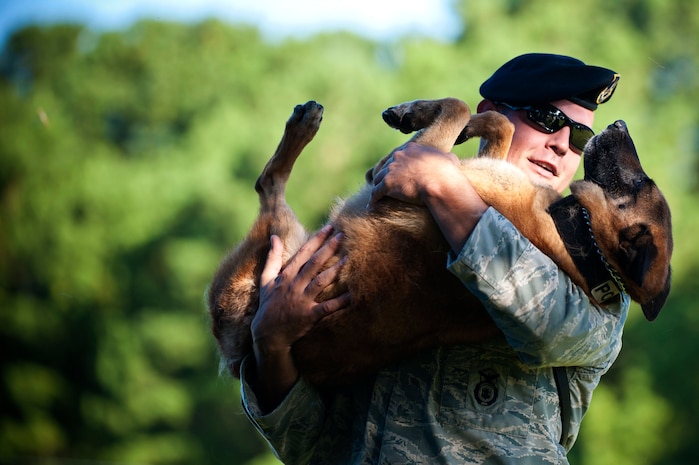 Staff Sgt. Timothy Garrett, 628th Security Forces Squadron K-9 handler , holds Military Working Dog Akim, a Belgian Malanois, during a K-9 demonstration for children from Eagle Harbor Boys Ranch, July 22, 2013, at Joint Base Charleston – Air Base, S.C. The boys watched a K-9 demonstration and were able to examine the 628th Security Forces Squadron patrol cars. The 628th Civil Engineer Squadron Fire Department also briefed the children about their jobs as firefighters gave them a tour of the fire station. (U.S. Air Force photo/ Staff Sgt. David Collins) 