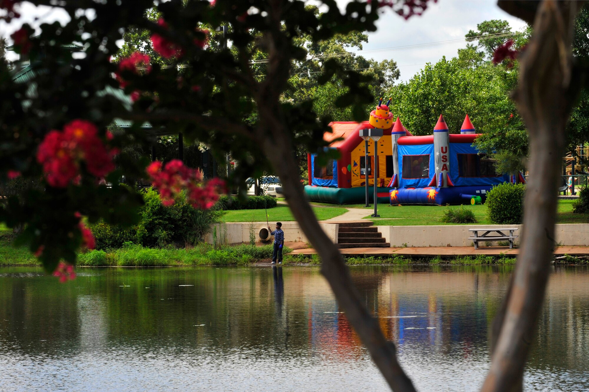 A child attempts to fish next to bouncy castles during a Hearts Apart event at Memorial Lake Pavilion, Shaw Air Force Base, S.C., July 20 2013.  The castles were used during the Hearts Apart event which gives families of deployed or remote tour Airmen a chance to have fun, relax, and network with other families.