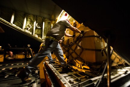 Civilians from the 437th Aerial Port Squadron push cargo onto a C-130J-30 from Dyess Air Force Base, Texas, during an early morning cargo load July 23, 2013, at Joint Base Charleston - Air Base, S.C. The C-130J-30 was loaded with rations and supplies bound for Bogota. The C-130J-30 is a stretch version of the C-130J, a proven, highly reliable and affordable airlifter. The C-130J-30 adds 15 feet to the fuselage, increasing usable space in the cargo compartment. (U.S. Air Force photo/ Senior Airman George Goslin)