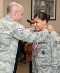 HANSCOM AIR FORCE BASE, Mass. – Col. Lester A. Weilacher, 66th Air Base Group commander, presents a medallion to Senior Airman Aniza Figueroa during Heroes Homecoming at the Hanscom Conference Center July 23. Among those honoring the Airmen at the celebration were community organizations and local professional sports figures as well as the Boston Red Sox World Series trophies. (U.S. Air Force photo by Rick Berry)