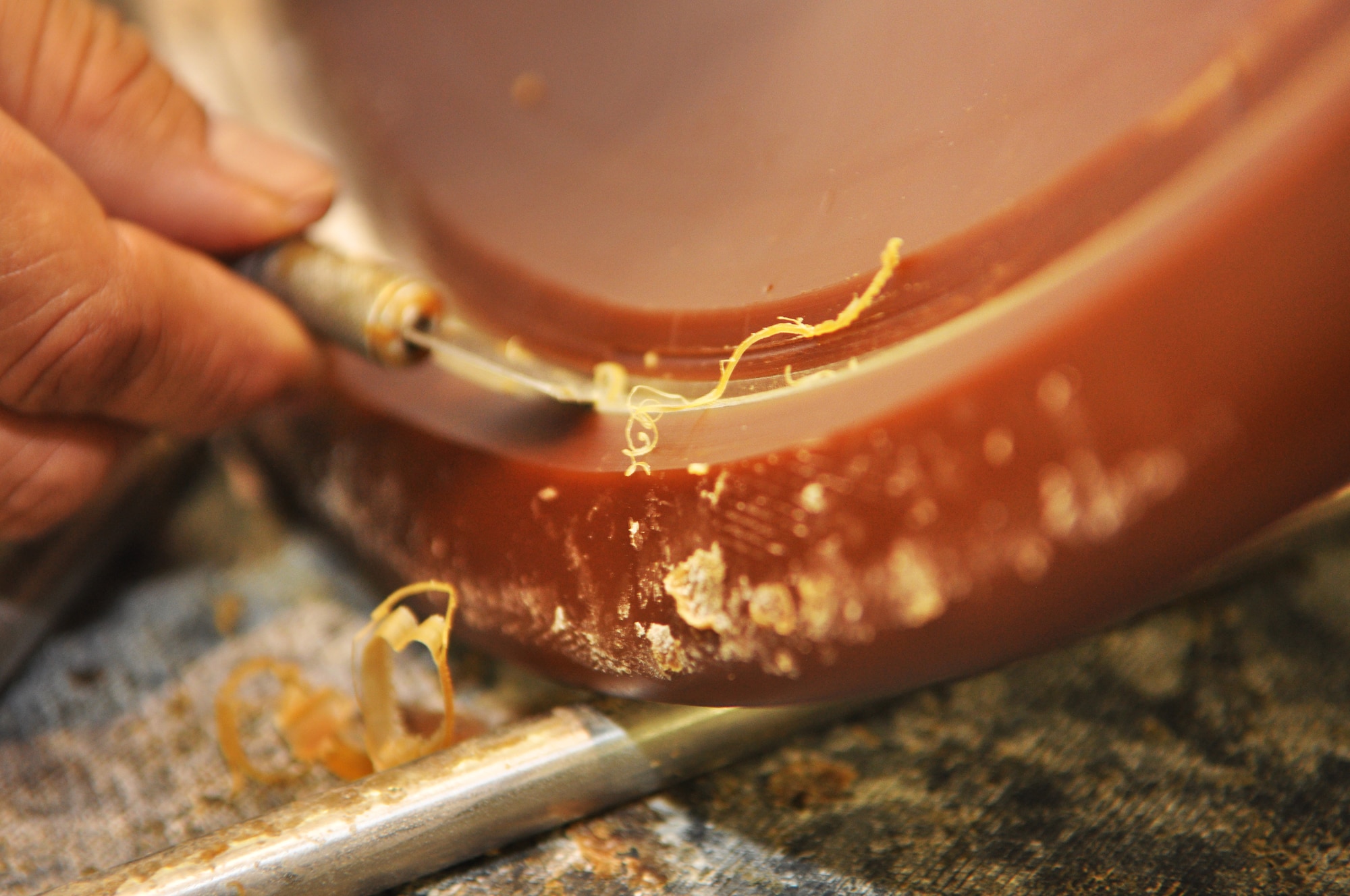 Mr. Tijerina uses a small tool, like an exacto knife, to scrape off the wax from the area of the engine part that will be plated with nickel. (Air Force photo by Micah Garbarino)