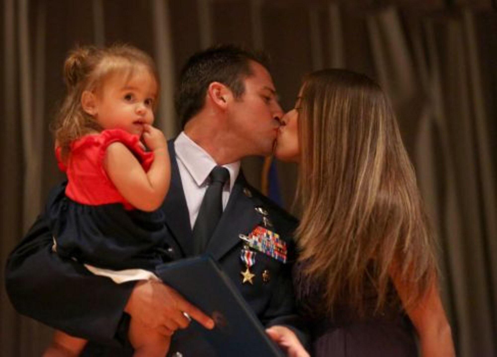 Staff Sgt. Dale C. Young from the 342nd Training Squadron holds his daughter Karina as he kisses his wife Rayna Young (cq) after being awarded a Silver Star during a ceremony at Joint Base San Antonio-Lackland on Monday July 22, 2013. Air Force Special Operations Command Lt. General Eric Fiel presented the commendations.(Photo By Helen L. Montoya/San Antonio Express-News)