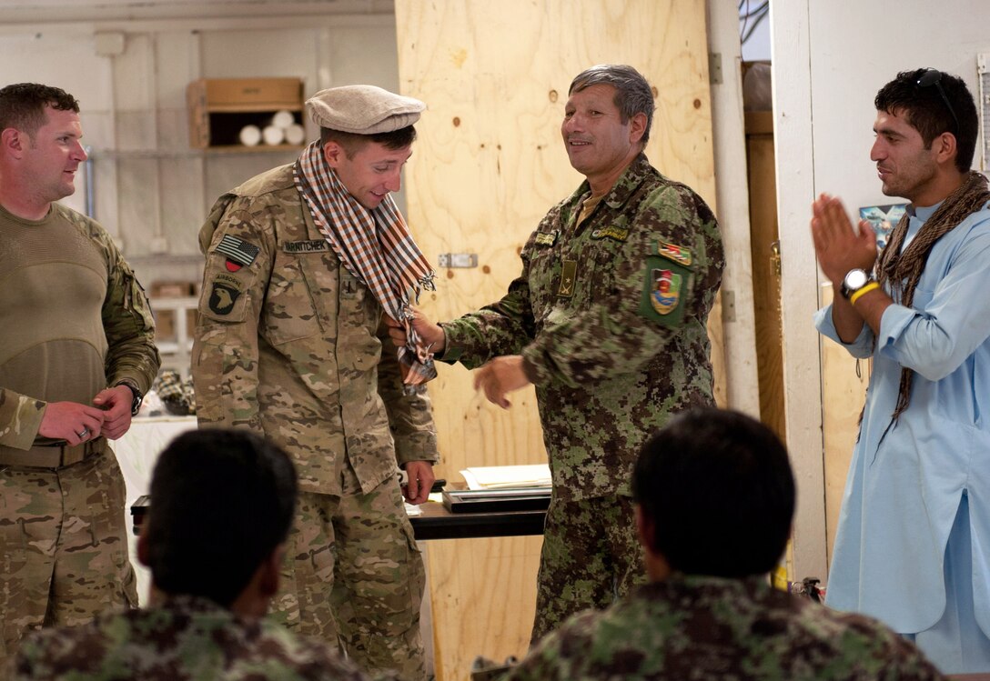 The Afghan army's deputy commander, right, gives U.S. Army 1st Lt. Kyle Harnitcheck the gift of a hat and scarf on former Forward Operating Base Shinwar in Nangarhar province, Afghanistan, July 14, 2013. Harnitchek is assigned to the 101st Airborne Division's 1st Battalion, 327th Infantry Regiment, 1st Brigade Combat Team.