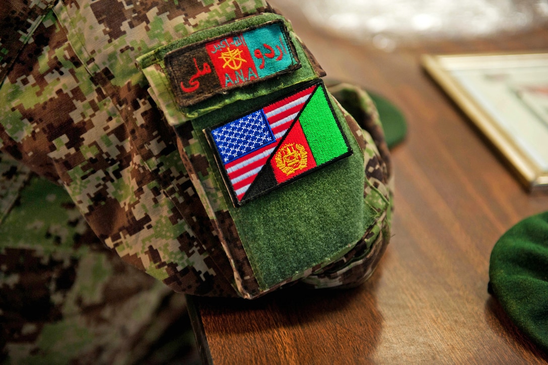 An Afghan soldier shows off a dual flag patch he received from U.S. soldiers during an appreciation ceremony on former Forward Operating Base Shinwar in Nangarhar province, Afghanistan, July 14, 2013.