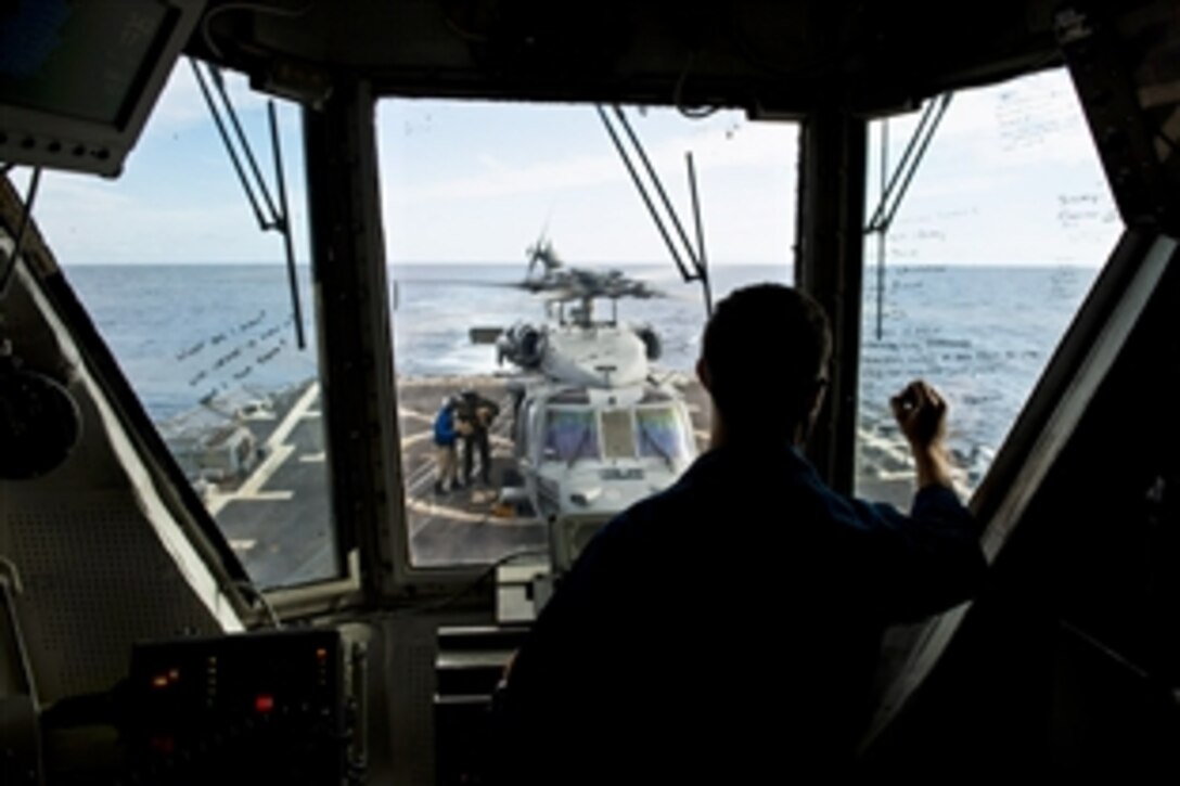 U.S. Navy Ensign Robert Martinez tracks an SH-60S Seahawk helicopter from Helicopter Sea Combat Squadron 12 as it prepares to take off from the flight deck of the guided-missile destroyer USS Preble in the Coral Sea, July 22, 2013. The Preble is participating in Talisman Saber 2013, a biennial training event to improve Australian and U.S. combat readiness and interoperability as a combined task force.