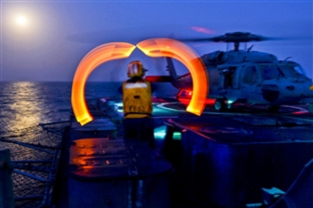 U.S. Navy Petty Officer 2nd Class Janet Lee signals to pilots assigned to Helicopter Sea Combat Squadron 26 on the flight deck of the guided-missile cruiser USS Monterey in the Arabian Gulf, July 22, 2013. The Monterey is deployed to support maritime security operations and theater security cooperation efforts in the U.S. 5th Fleet area of responsibility. Lee is a boatswain's mate.