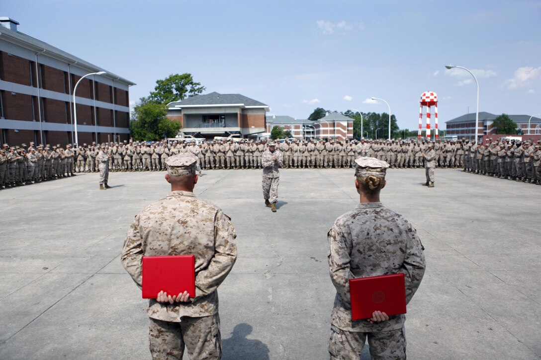 Sgt. Kirby D. Kuhn and Sgt. William P. Goodacre, combat instructors with School of Infantry - East, Combat Training Battalion, Company F., recieve applause from their chain of command, fellow combat instructors and students after recieving Navy and Marine Corps Achievement Medals during an awards ceremony aboard Camp Geiger, June 17. Kuhn and Goodacre used their training to get a Marine who started seizing to breathe again and saved her life during a M203 grenade launcher practical application exam, May 26.