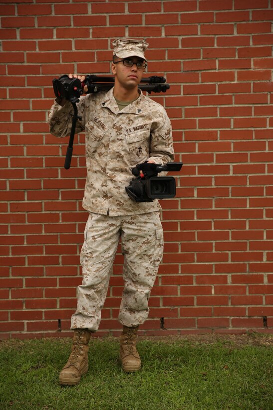 Cpl. Hector L. Dejesus poses for the camera with his tripod July 23 in front of the station combat camera building.  
