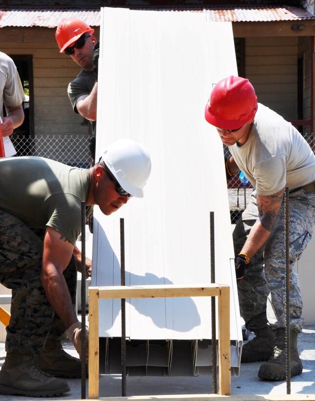 U.S. Marine Corps Staff Sgt. Daniel Guerrero, senior staff noncommissioned officer in charge from Marine Wing Support Squadron 471, and U.S. Air Force Staff Sgt. Matthew Morrison, structures supervisor for the 823rd RED HORSE Squadron, set the exterior walls of the Crooked Tree Government Primary School.  Engineers from both the U.S. and Belize are constructing various structures at schools throughout Belize as part of exercise New Horizons. (U.S. Air Force photo by Capt. Holly Hess/Released)