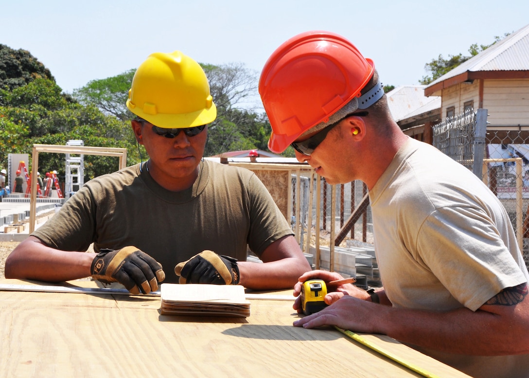 U.S. Air Force Senior Airman Ryan Peters (right), structural worker for the 823rd RED HORSE Squadron, and U.S. Marine Corps Lance Cpl. Christopher Calderon, a combat engineer from Marine Wing Support Squadron 471, analyze how to best use plywood and avoid waste for roof-truss construction at Crooked Tree Government Primary School. Engineers from both the U.S. and Belize are constructing various structures at schools throughout Belize as part of exercise New Horizons.  (U.S. Air Force photo by Capt. Holly Hess/Released)